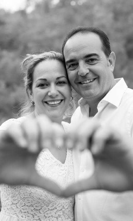 Cinthya y David sonriendo, en blanco y negro, formando un corazón con las manos